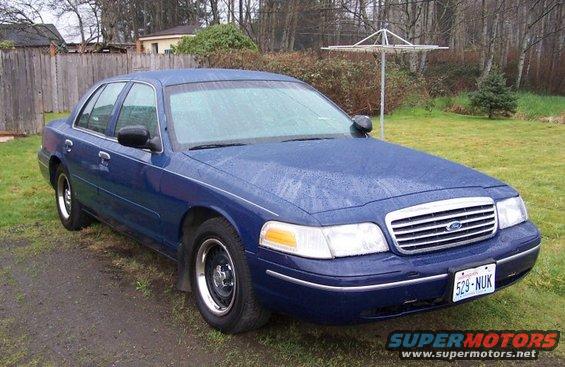 Blue 1998 Ford Crown Victoria sedan parked on a grassy area with a dirt path