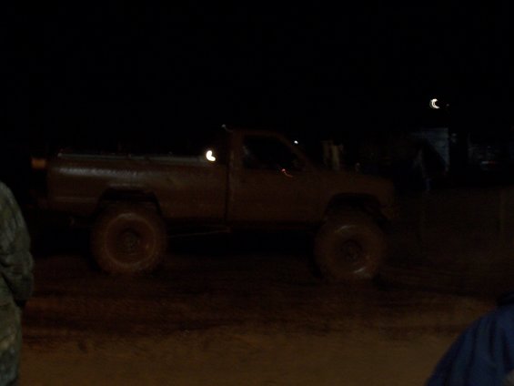 Muddy pickup truck with large tires at night