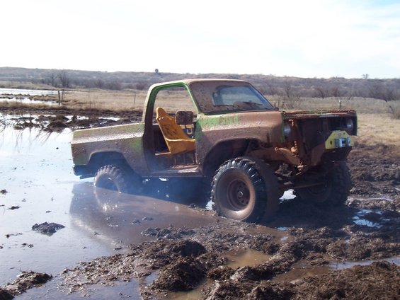 Muddy pickup truck with missing front end stuck in a mud bog