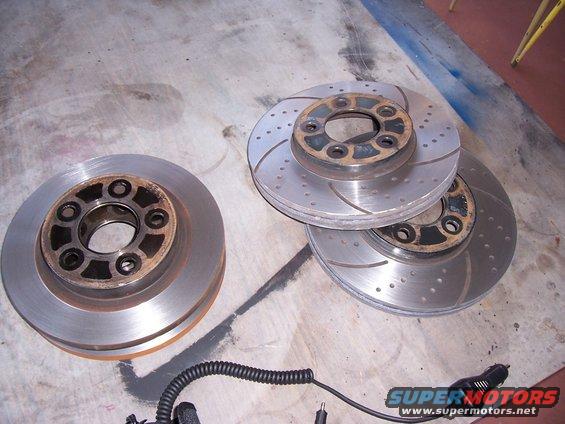 Two brake rotors on the left, three stacked on the right. One rotor on the left is solid, the others are drilled and slotted