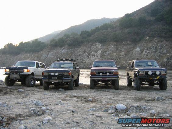Four SUVs parked on a rocky shore, one is a 1987 Ford Bronco