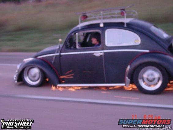 Dark Volkswagen Beetle with sparks flying from its side, roof rack, and custom wheels