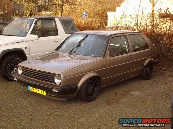 Brown Volkswagen Golf Mk2 with black wheels, lowered suspension, and a yellow license plate