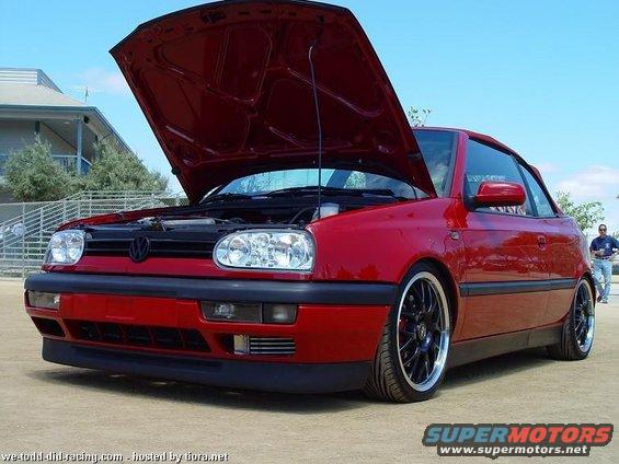 Red Volkswagen convertible with hood open, front view, black aftermarket wheels, lowered suspension