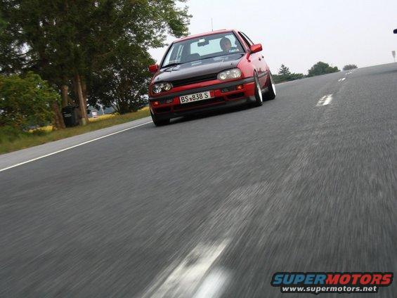 Red hatchback with black hood and license plate BS-838 S driving on a road