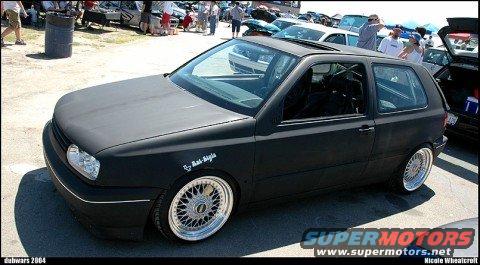 Matte black Volkswagen Golf GTI with aftermarket wheels and a roll cage visible inside