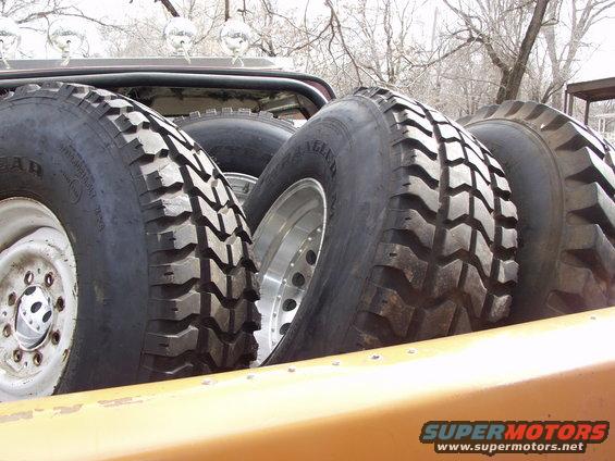Several large off-road tires stacked in a vehicle bed. One tire has 'WRANGLER' visible