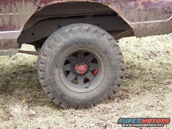 muddy off-road tire on a vehicle, showing part of the fender and suspension