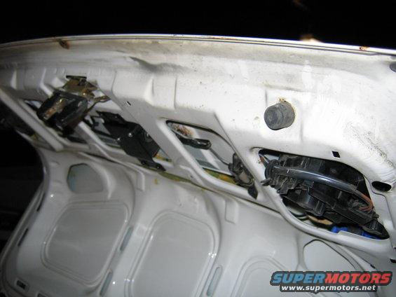 Interior of a white car's trunk lid showing latches and wiring