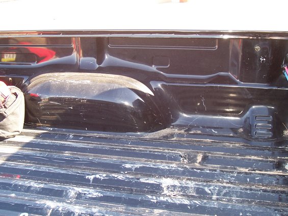 Black truck bed with visible wheel well and ribbed floor