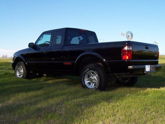 Black 2003 Ford Ranger Edge pickup truck parked in a grassy field with a windmill in the background