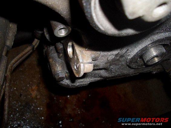 Close-up of a greasy engine component with bolts and metal brackets