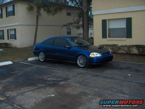 Blue coupe with a black hood parked in a lot, 3/4 front view