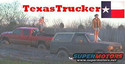 Dark 1989 Ford Bronco with a person standing on its hood, stuck in mud next to a red pickup truck