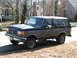 1996 Ford Bronco - This Ford Bronco SUV is parked on a street with houses and trees in the background.