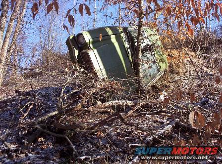 overturned green vehicle in woods