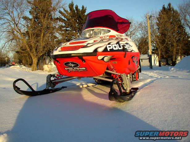Red and white snowmobile with 'POLARIS' text and flame graphics, parked in snow