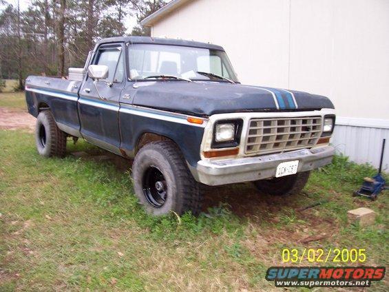 1979 Ford F-150 pickup truck, dark blue with white and blue side trim, parked on grass