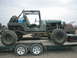 1983 Ford Bronco - Customized Jeep CJ-7 loaded onto a trailer, with a red SUV visible in the background.