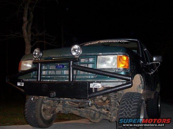Green Ford F-Series truck with aftermarket bumper and lights. Has a "Texas Truck Works" sticker on windshield