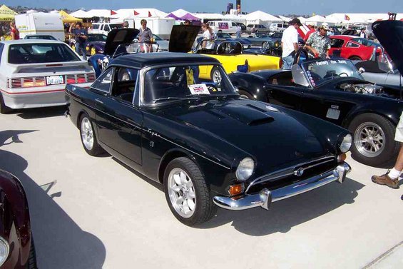 Dark green coupe with a scoop on the hood parked next to a white car and a black convertible