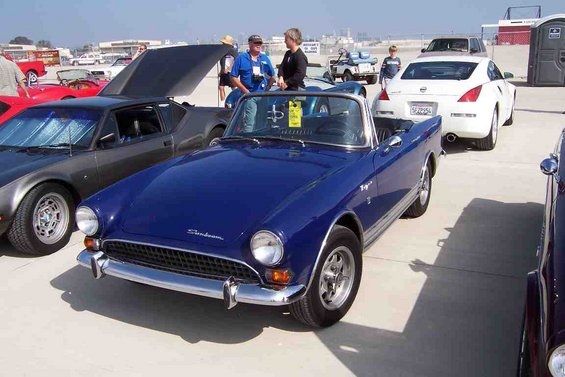 Blue convertible sports car with chrome trim and wire wheels parked outdoors