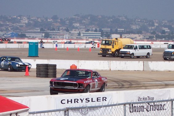 Red 1969 Ford Mustang racing car with black hood and racing numbers on side