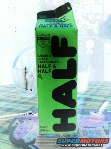 Green carton of half and half on a table with a glass