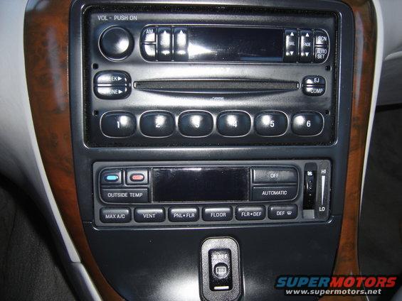 Car interior dashboard with wood trim, radio, and climate controls. Includes buttons for 'MAX A/C', 'VENT', 'FLOOR', and 'DEF'