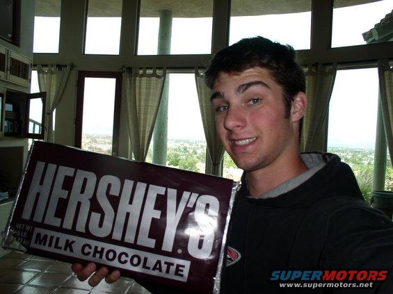 guy holding a huge Hershey's milk chocolate bar indoors