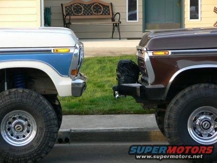 Two 1979 Ford Broncos parked front-to-front, one white and blue, the other brown