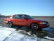 1999 Ford Crown Victoria - A red sedan is parked on a wet asphalt lot with snow on the ground under a clear blue sky.