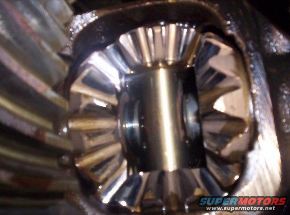 Close-up of differential gears with oil, showing wear on teeth