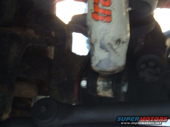 Close-up of a shock absorber with orange lettering, part of a vehicle's suspension