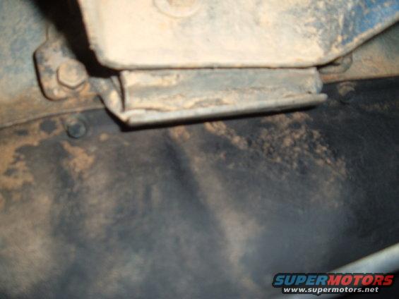 Close-up of a rusty metal bracket attached to a vehicle frame