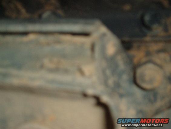 Close-up of a dirty vehicle frame with bolts and suspension parts visible