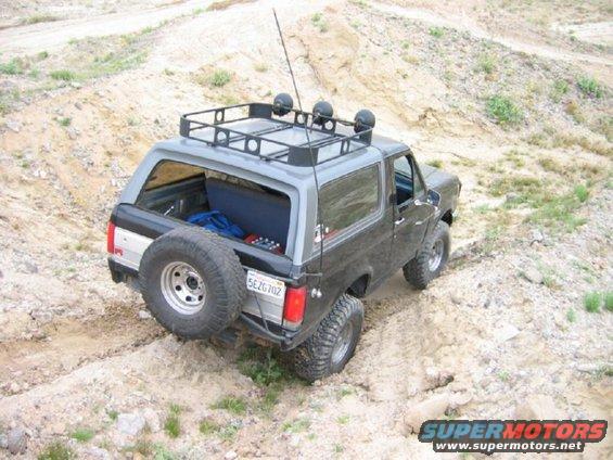 1988 Ford Bronco with roof rack and spare tire on a dirt trail