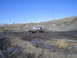1981 Ford Bronco - A Ford Bronco navigates a challenging muddy terrain under a clear blue sky.