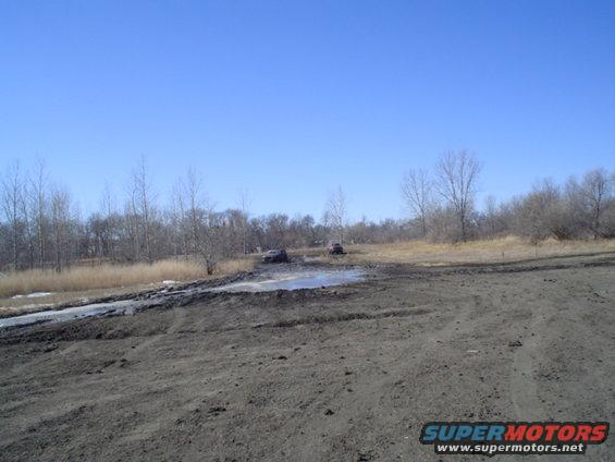 Two SUVs stuck in mud under a clear blue sky