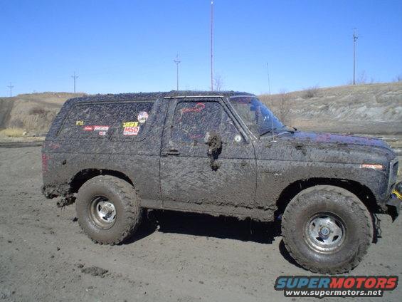 Mud-covered SUV, side view, with stickers on the door