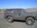 1981 Ford Bronco - This heavily muddied SUV is seen from the side under a clear blue sky.