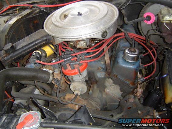Engine bay with distributor, air cleaner, and spark plug wires visible. Some rust and grime present