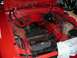 1978 Ford Mustang II - Engine bay of a red car, missing its engine, showing brake booster and wiring.