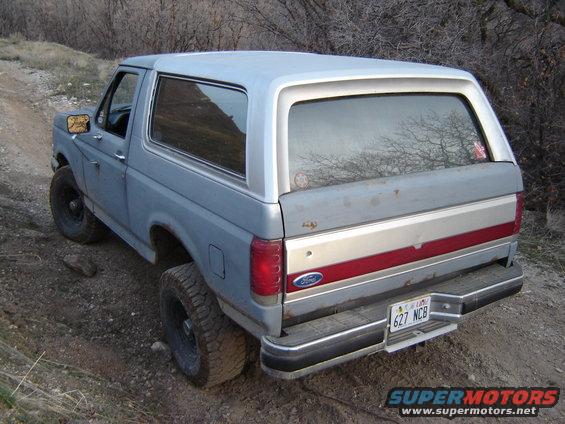 Rear view of a light blue 1991 Ford Bronco on a dirt road