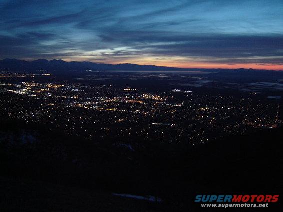 City lights spread across a valley at dusk with mountains in the background