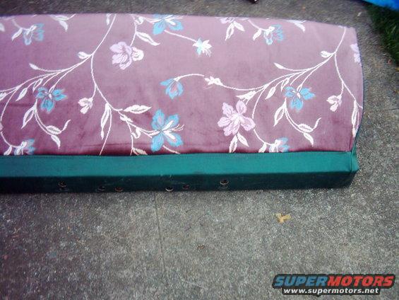 Floral patterned seat cushion with green base, sitting on concrete