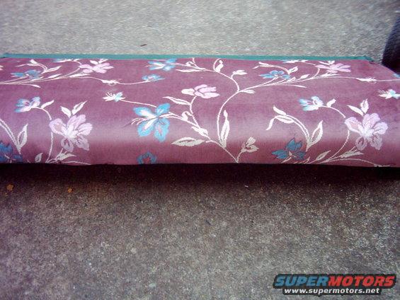 Floral upholstered seat cushion with purple and pink flowers on a concrete surface