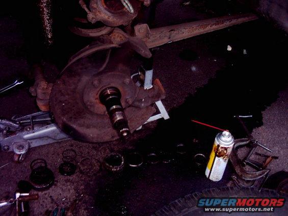 Disassembled brake rotor and hub assembly with tools and spray can on the ground