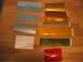 2002 Ford Taurus - Various paint swatches are laid out on a wooden surface, including gold, copper, yellow, green, red, and silver samples.