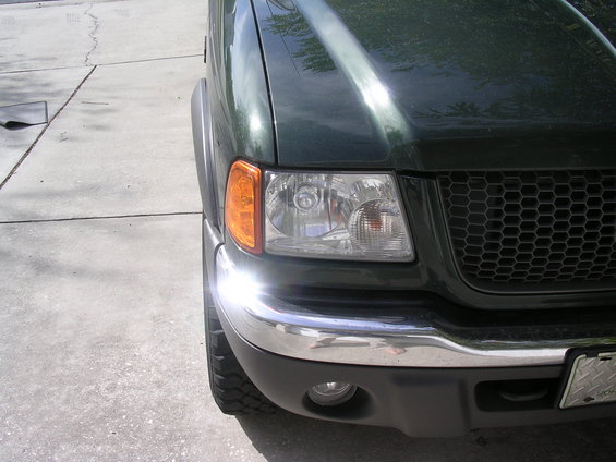 Green pickup truck front corner with chrome bumper and honeycomb grille